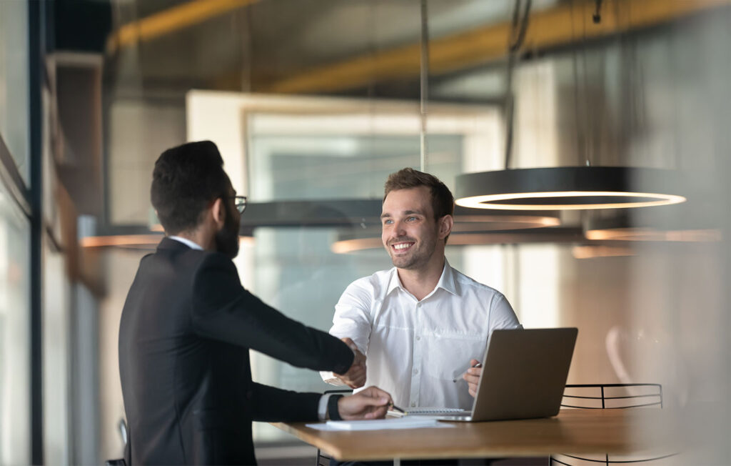Business professionals shaking hands over an office lease agreement in a modern workspace.
