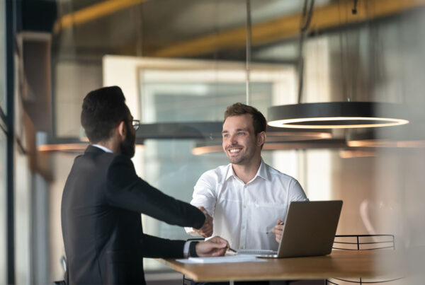 Business professionals shaking hands over an office lease agreement in a modern workspace.